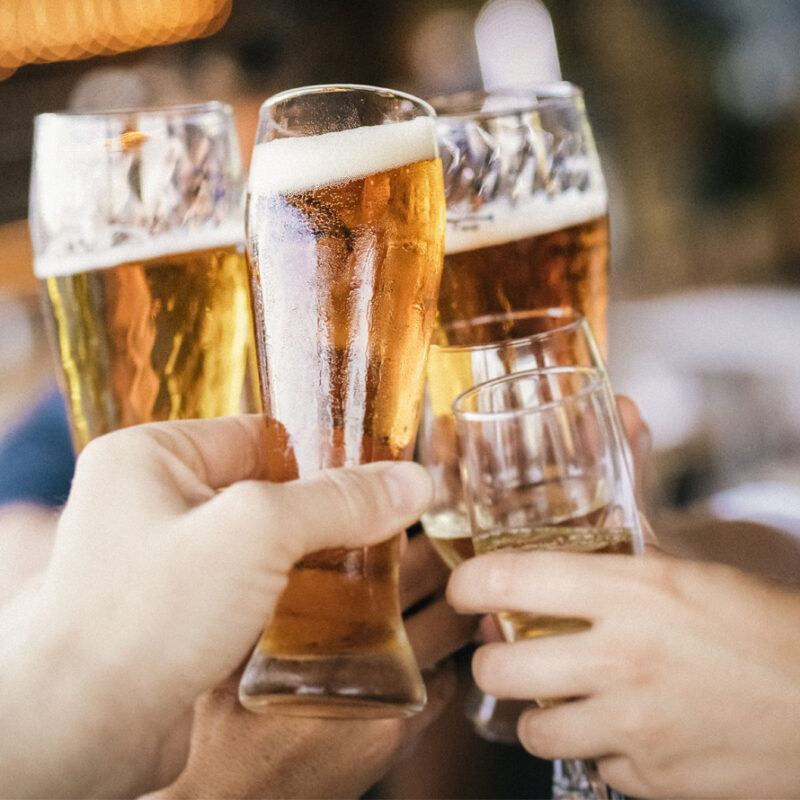 Closeup shot of male and female hands toasting with pints of beer