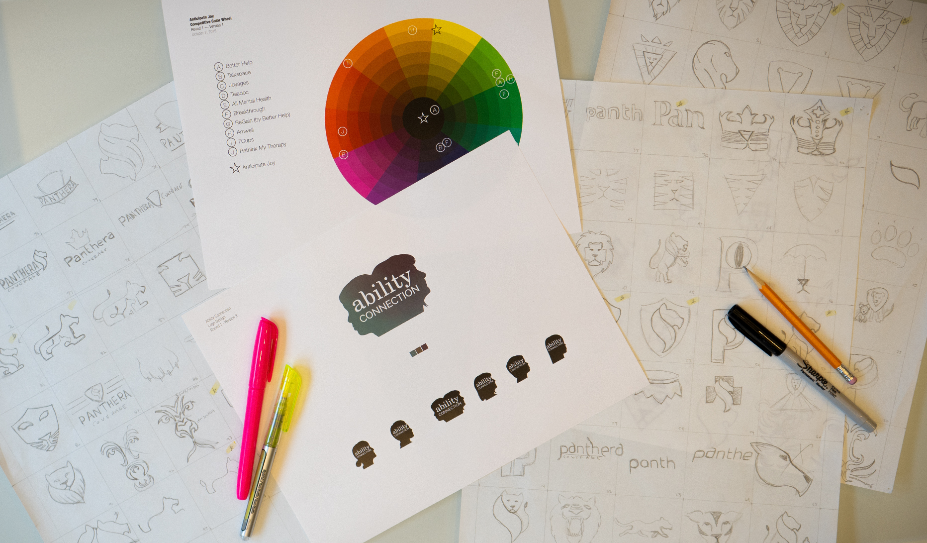 Table with logo sketches, color wheel and logo printout